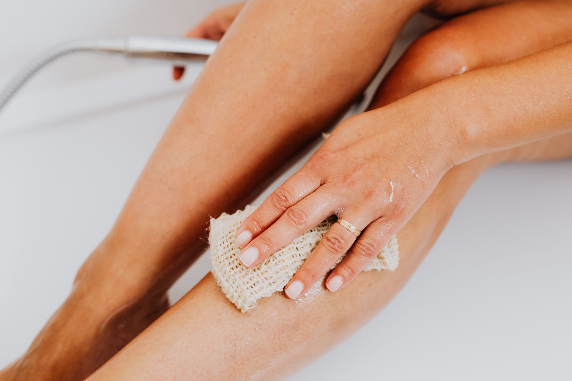 Femme qui s'exfolie les jambes avant une séance d'épilation à la cire à Montréal