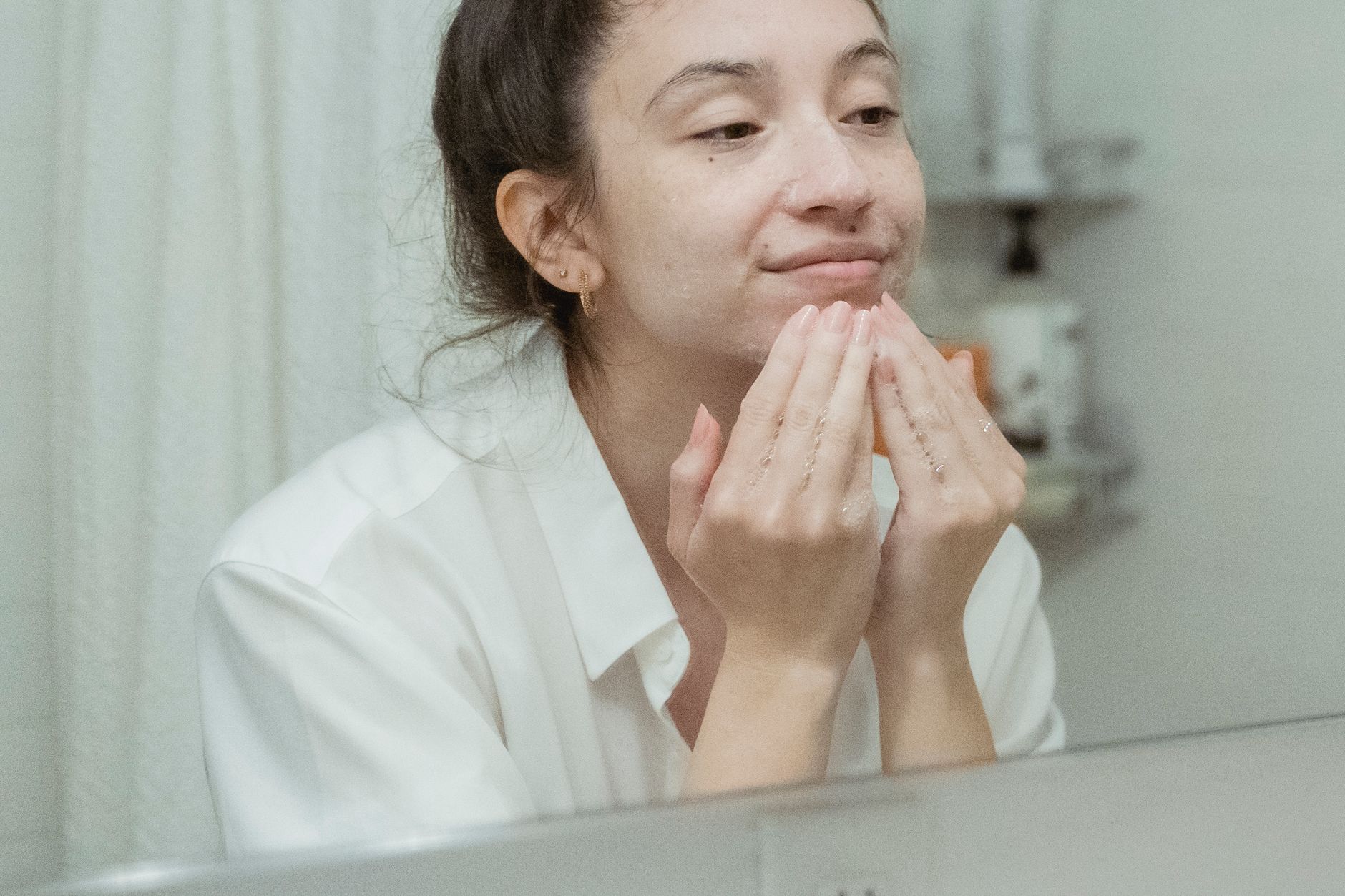 Femme avec une peau lumineuse après un soin visage Montréal, routine du matin devant le miroir